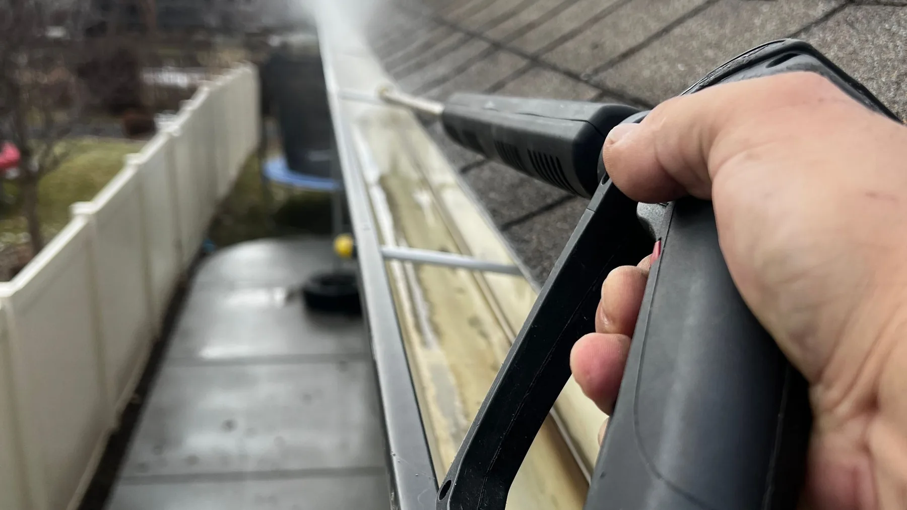 Residential roof gutter being cleared with a cleaning tool